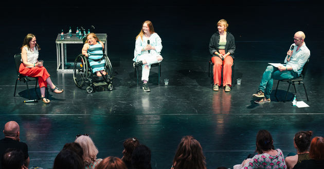 Auf der Bühne der fabrik Potsdam sitzen von links nach rechts die Panelist*innen des Panels „Was bedeutet Inklusion in der Schauspielausbildung?“  Alrun Hofert, Jana Zöll, Amelie Gerdes, Hanna Frank und der Moderator Georg Kasch vor einem Publikum. Alrun Hofert spricht gerade und lächelt dabei.